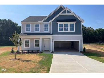 Two story home with a blue and grey exterior, open garage, and large concrete driveway at 129 Sagamore Avenue, Angier, NC 27501
