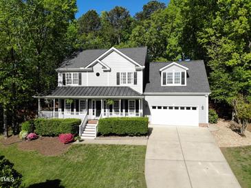 Charming two-story home with a covered front porch, well-manicured lawn, and attached two-car garage at 141 Clay Ridge Way, Holly Springs, NC 27540