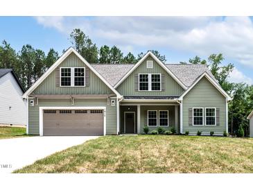 Charming green two-story home featuring a two-car garage and well-manicured lawn at 1412 Sagamore Dr, Louisburg, NC 27549