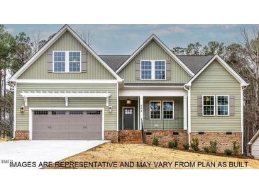 Charming two-story home with sage green siding, attached two-car garage, and inviting front porch at 1412 Sagamore Dr, Louisburg, NC 27549