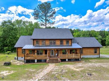 Charming two-story log home with a welcoming covered front porch and beautiful landscaping at 2092 Winwood Farm Rd, Creedmoor, NC 27522