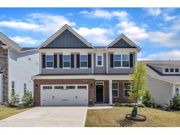 Charming two-story home with a brick facade, two-car garage, and manicured front yard at 2100 Curry Meadow Way, Durham, NC 27703
