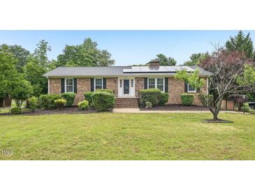 Charming brick ranch with solar panels, a well-maintained lawn, and mature landscaping at 2606 Newquay St, Durham, NC 27705