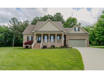 Charming brick home with a welcoming front porch, attached garage and lush green lawn at 4667 Freedom Dr, Burlington, NC 27215
