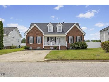 Charming brick home featuring a cozy front porch, black shutters, and lush green lawn at 1104 Cross Creek Dr, Nashville, NC 27856