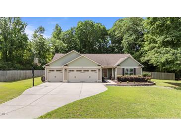 Charming single-story home with a well-manicured lawn, three-car garage, and extended driveway with basketball hoop at 123 Terawood Farm Dr, Willow Springs, NC 27592