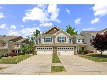 Beautiful townhome featuring an attached two-car garage and manicured lawn, offering modern convenience at 221 Mayfield Dr, Apex, NC 27539