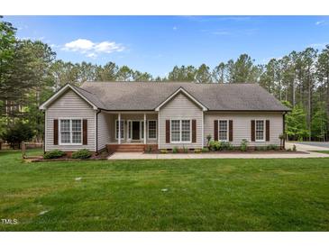 Charming single-story home featuring a manicured lawn, symmetrical windows, and professional landscaping at 3653 Range Rd, Stem, NC 27581