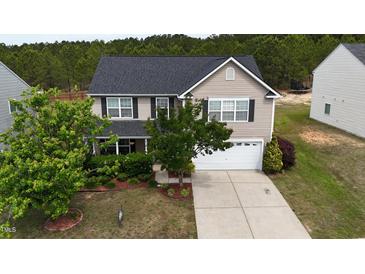 Traditional two-story home featuring a two-car garage, well-maintained lawn, and mature trees at 126 Thimbleweed Ln, Lillington, NC 27546