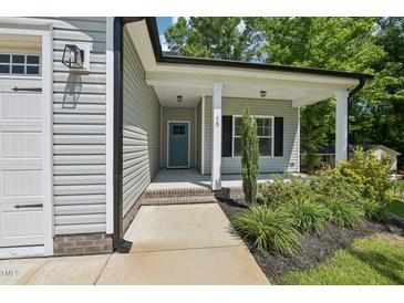 Charming home featuring a covered entrance, well-manicured landscaping, and a welcoming blue door at 15 Nottingham Pl, Smithfield, NC 27577