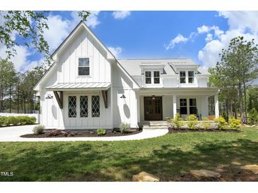Charming two-story white farmhouse with a covered porch and well-maintained landscaping at 2200 Mays Crossroads Rd, Louisburg, NC 27549