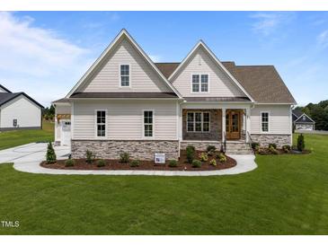 Inviting home featuring a stone foundation, manicured lawn, beautiful landscaping, and a charming front porch at 25 Deer Tail Ln # 52, Fuquay Varina, NC 27526