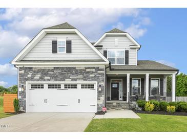 Charming two-story home with stone accents, two-car garage, and manicured lawn at 4504 Beckel Rd, Willow Springs, NC 27592