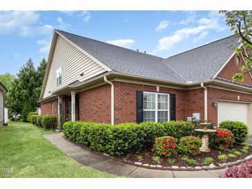 Charming brick home featuring manicured landscaping, green lawn, black shutters, and a delightful water fountain at 8005 Crookneck Dr, Angier, NC 27501