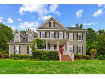 Charming two-story home with a well-manicured lawn, inviting porch, and a vibrant red front door at 809 Parkridge Dr, Clayton, NC 27527