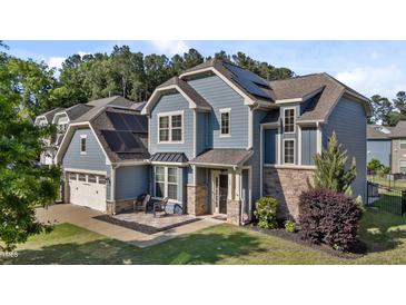 Beautiful two-story home with blue siding, stone accents, solar panels and a charming front patio at 94 Pearsall Farm Ln, Clayton, NC 27527