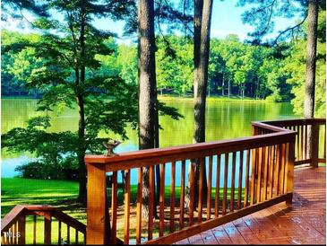 Inviting lake view from a wood deck featuring wooden rails and stairs surrounded by mature trees at 11813 Edgewater Ct, Raleigh, NC 27614