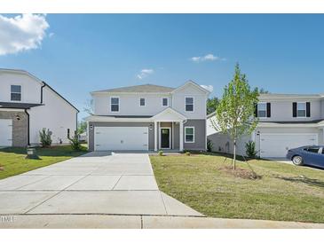 Charming two-story home boasts a well-manicured lawn, inviting driveway, and attached two car garage at 1730 Pie Filling Dr, Haw River, NC 27258