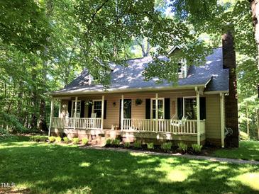 Charming home with a rocking chair front porch surrounded by mature trees and lush lawn at 2603 Red Pine Rd, Hillsborough, NC 27278