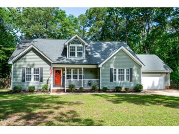 Charming single-Gathering home featuring a well-manicured lawn, a cozy front porch, and a bright red front door at 305 Monterey Ct, Benson, NC 27504