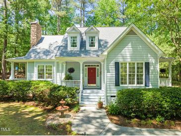 Charming home featuring a welcoming red door, stone chimney, and lush green landscaping at 3201 Keighley Forest Dr, Wake Forest, NC 27587