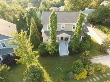 Inviting two-story home with a charming front porch, well-manicured lawn, and mature trees providing ample shade at 457 S Greensboro St, Carrboro, NC 27510