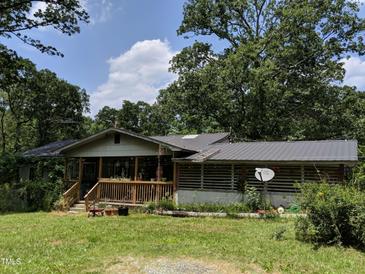 Quaint single story home with a covered front porch and metal roof surrounded by mature trees on a sunny day at 6010 Bonlee Bennett Rd, Bear Creek, NC 27207