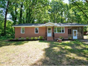 Charming brick home featuring a well-maintained lawn and a screened in porch in a tranquil, wooded setting at 6017 Whitaker Ln, Raleigh, NC 27603