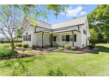 Charming white home with metal roof, landscaped yard, and inviting front porch at 7227 Cleveland Rd Rd, Clayton, NC 27520