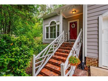Charming front entrance with brick steps, white railing, and vibrant green foliage at 8 Wexford Dr, Durham, NC 27713