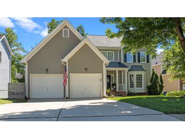 Charming two-story home featuring a two-car garage, manicured lawn, and a welcoming front porch and an American flag at 8724 Deerland Grove Dr, Raleigh, NC 27615