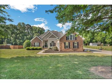 Charming brick and siding home with lush lawn, mature trees and well-maintained landscaping at 95 Live Oak Dr, Louisburg, NC 27549