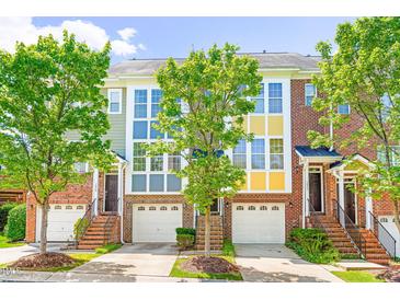 Charming townhome with brick facade, garage, and lush green trees on a sunny day at 1028 Summerhouse Rd, Cary, NC 27519