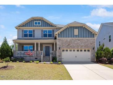 Charming two-story home with a combination of stone and shingle siding, complemented by a well-manicured lawn at 105 Blue Prince Trl, Holly Springs, NC 27540