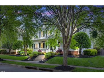 Charming two-story home with a inviting front porch and beautiful landscaping at dusk at 10523 Bedfordtown Dr, Raleigh, NC 27614