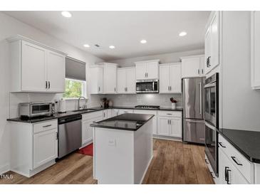 Modern kitchen features white cabinetry, stainless steel appliances, granite counters, and a functional center island at 170 Creekhaven Dr, Angier, NC 27501