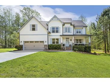 Charming two-story home featuring a covered porch, well-manicured lawn, and attached two-car garage at 1723 River Club Way, Franklinton, NC 27525