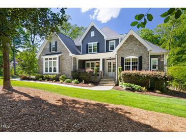 Charming two-story home with stone and shingle siding, manicured lawn, and inviting front porch at 30 Ocoee Falls Dr, Chapel Hill, NC 27517