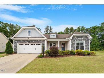 Charming single Gathering home featuring stone accents and a well-manicured lawn at 704 Long Lake Dr, Fuquay Varina, NC 27526