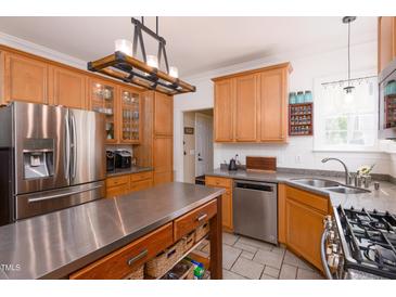 Bright kitchen features stainless steel appliances, an island, and light wood cabinetry at 8517 Falkirk Ridge Ct, Wake Forest, NC 27587