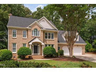 Charming brick home with a manicured lawn, elegant doorway, and attached two-car garage in a lush, green setting at 108 Nimbus Ct, Cary, NC 27513