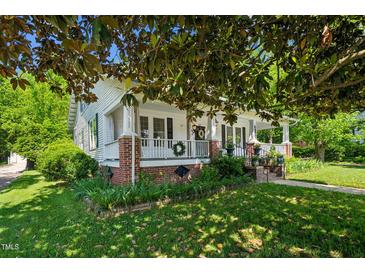 Charming home featuring a welcoming front porch, brick accents, and lush landscaping at 1111 College St, Oxford, NC 27565