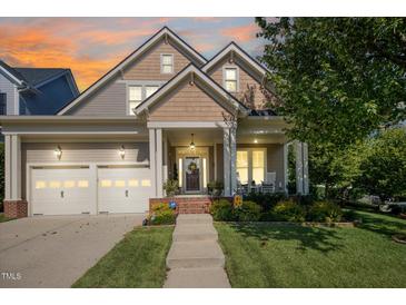Inviting exterior view of a two-story home featuring a well-manicured lawn, two-car garage, and charming front porch at 121 Bridgegate Dr, Cary, NC 27519