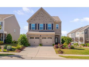 Charming two-story brick home featuring a two-car garage, well-manicured lawn, and colorful landscaping at 1904 Birdhouse Ln, Wake Forest, NC 27587