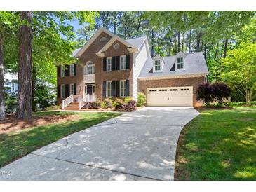 Charming brick home with a two-car garage and inviting front yard, nestled among mature trees at 206 Kettlebridge Dr, Cary, NC 27511
