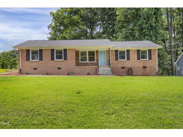 Charming brick home featuring a well-manicured lawn and a vibrant blue front door at 207 Mcleod Dr, Sanford, NC 27330