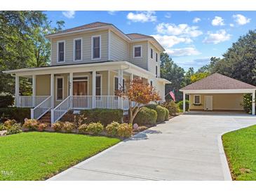 Charming two-story home featuring a classic porch, manicured lawn, and detached garage at 207 N Hopkins Ave, Spring Hope, NC 27882
