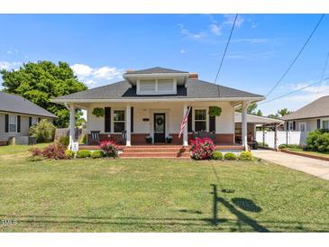 Charming home featuring a brick front porch, lawn, and cozy seating, inviting relaxation and curb appeal at 404 W E St, Erwin, NC 28339