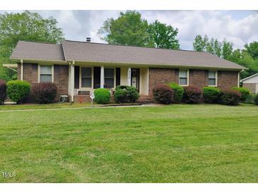 Charming brick home featuring a well-manicured lawn and mature landscaping at 4908 Mandel Rd, Durham, NC 27712