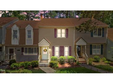 Charming townhome featuring lush landscaping, purple shutters, and inviting entryway at 704 Benchmark Dr, Raleigh, NC 27615